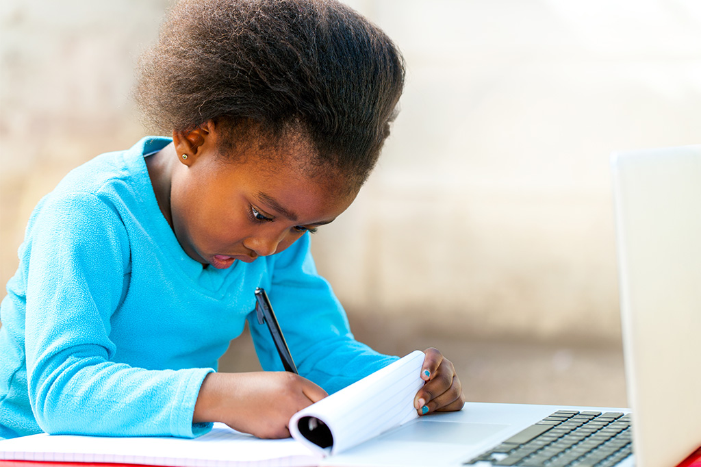 young child writing with pen and paper