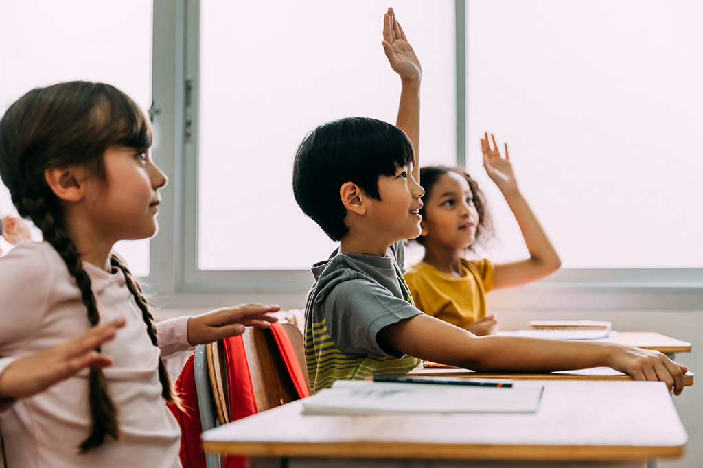 Child with their hands up in class