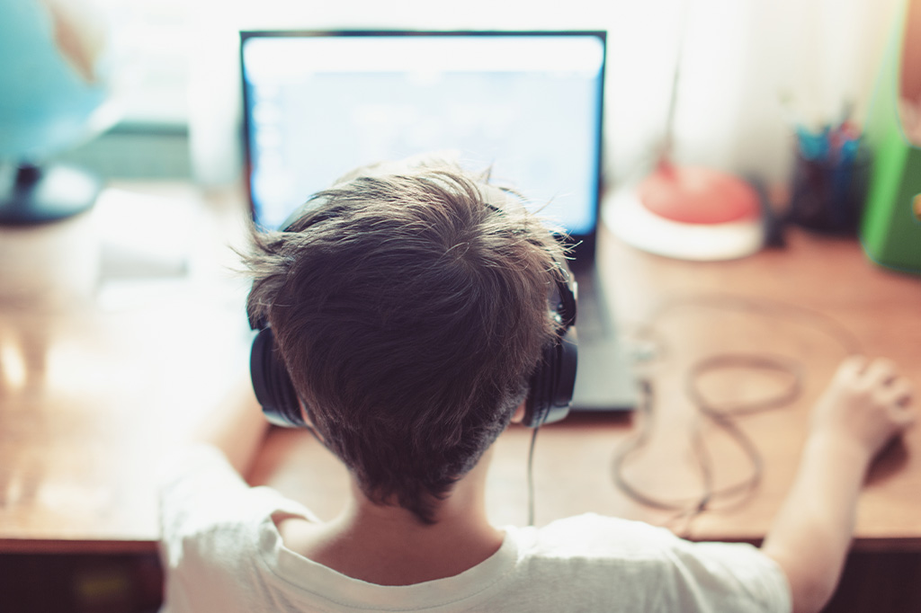 child concentrating on computer with headphones